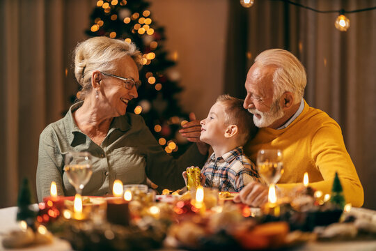 A senior couple is cuddling and hugging their grandson at christmas table on christmas and new year's eve.