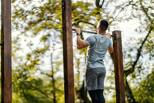 Sportsman doing chin ups in outdoor gym in nature. - Powered by Adobe