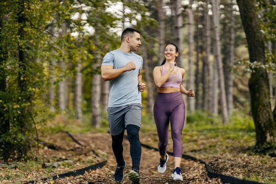 Nature fitness. A happy sporty couple is running in woods.