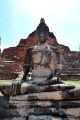 Old Buddha statue in Thailand ancient temple with historical building background