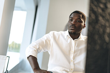 Obraz premium Young African man sitting against mirror indoors