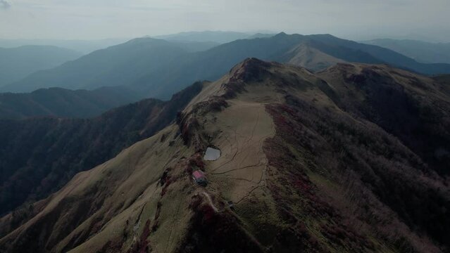 Drone flight over Mt Miune in Shikoku, Japan during Autumn. The mountains shows high contrast of green and red leaves.