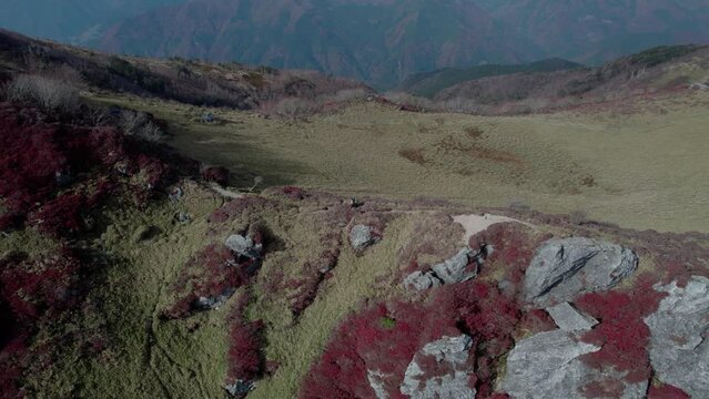 Drone flight over Mt Miune in Shikoku, Japan during Autumn. The mountains shows high contrast of green and red leaves.