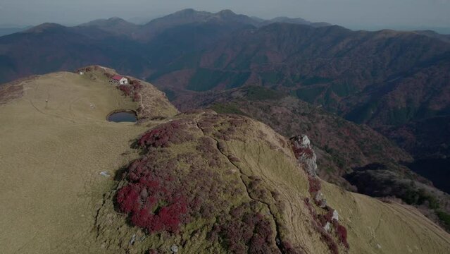 Drone flight over Mt Miune in Shikoku, Japan during Autumn. The mountains shows high contrast of green and red leaves.