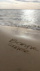 Message happy new year in french text sign means bonne annee written on beach sand background New Year coming concept