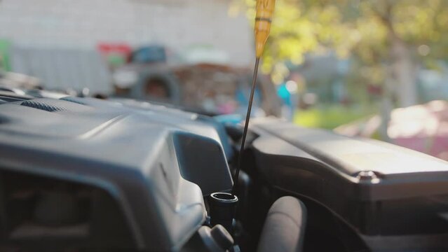 Removing the oil dipstick from the engine to check the engine oil level. Slow motion, close-up