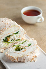 Homemade Meringue Cake Sweets Roll with kiwi jam on ceramic cutting board.