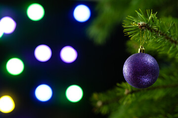 Christmas composition. Blue ball on a Christmas tree closeup on a sparkling dark background