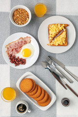 Hearty homemade family breakfast. Eggs, bacon, sausages, beans, croissants, toast and coffee on the table. Top View