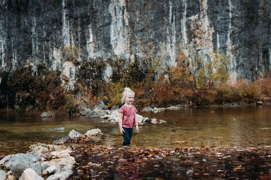 Young child wading in river during autumn day