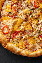 traditional Italian pizza with salami and vegetables on a black