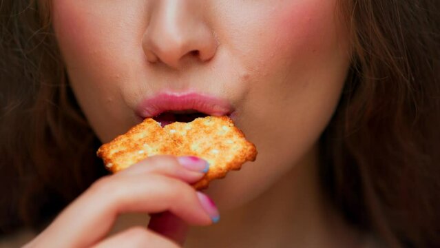 Portrait of Young Woman Eating Sweet Food on Camera Close Up. Crop Face of Modern Person Biting Crunchy Sesame Cookie in Mouth. Normal Appetite of Alone Hunger Lady with Crispy Treat in Studio Light
