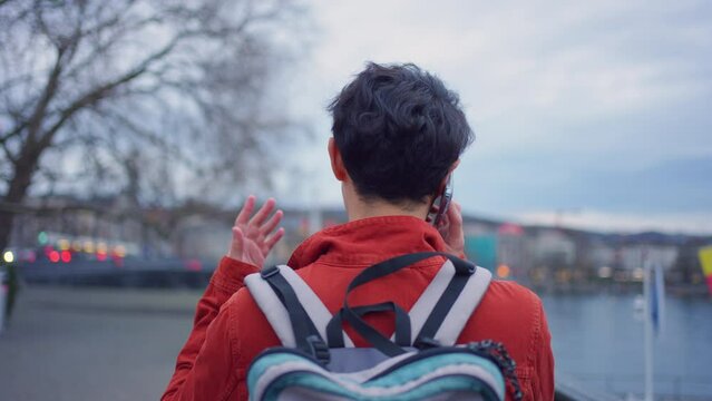 Asian young man backpacker talking on the phone while walking in city.