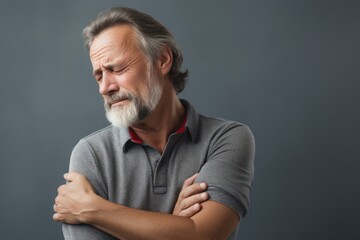 People, healthcare and problem concept - unhappy man suffering from neck or shoulder pain at home. Mature bearded man has shoulder pain. with copy space for text. Man holding his injured shoulder - obrazy, fototapety, plakaty