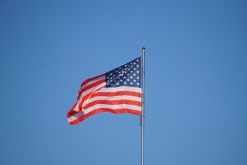 American Flag . USA national flag waving on wind against blue sky. Slow motion