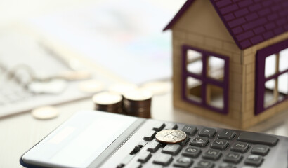 Coin Lay on Calculator, House Model on Office Desk. Sale of Real Estate Items Close Up Shot Partial...