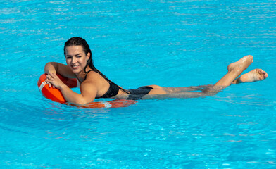A girl with a lifebuoy swims in the pool