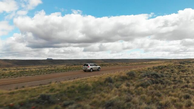 Aerial orbit around car on dirt road at Pilot Butte Wild Horse Scenic Loop, Wyoming USA.