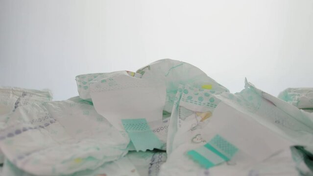 a lot of scattered baby diapers on a white background. The concept of natural cotton diapers, hypoallergenic and comfortable. Leakage protection. Copy space for text. Slow motion