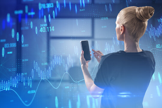 Attractive young businesswoman using cellphone with glowing candlestick forex chart on blurry office interior background. Stock market and investment concept. Toned image. Double exposure.