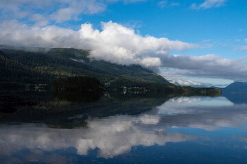 Fototapeta na wymiar Clouds and mountains reflecting on fjord in Norway