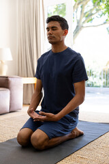 Fototapeta na wymiar Biracial man doing yoga and meditating at home