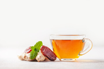 Hot warming tea with dates and ginger in a glass cup on the table. Immune drink - obrazy, fototapety, plakaty