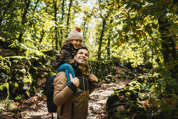 Photographer father and his fashionable son with a hat on his shoulders, happy, walking through a...