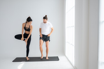 Obraz premium Young couple practicing yoga in a white room of studio.