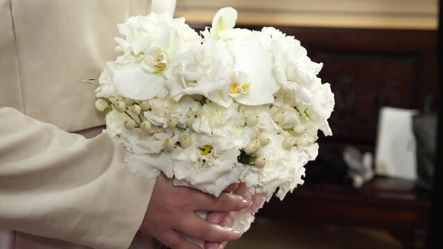 During the wedding ceremony, the bride holds a beautiful white bouquet of flowers in her hand.