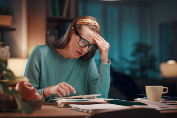 Stressed woman checking bills at home