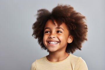 Portrait of a cheerful young girl with curly hair smiling on a light background.
