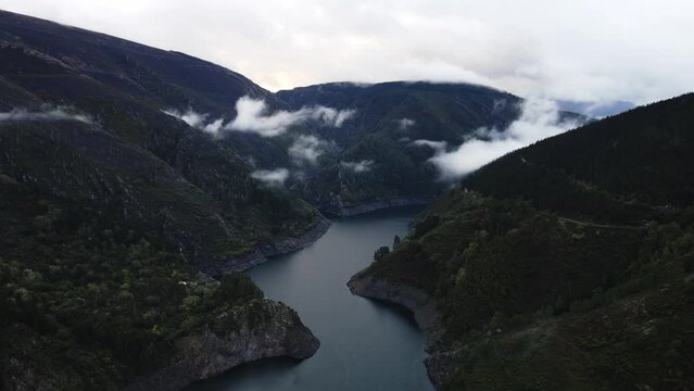 Forest wilderness mountain surrounded lake partly clouded aerial view