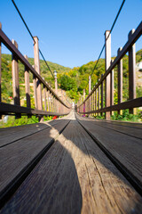 Obraz premium Historical wooden suspension bridge. Adventure wooden rope suspension bridge in the rainforest. Wooden suspension bridge leading to the waterfall. Ağaran Waterfall. Rize, Türkiye.