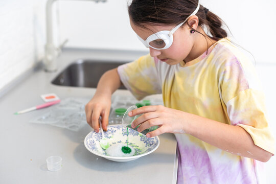 Enthusiastic little girl doing home science project, having a eureka moment. She has chemistry glassware with colorful liquids