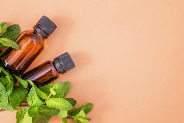 Essential oils bottles with bunch of peppermint on the beige background, aromatherapy, copyspace....