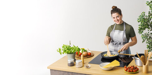 Happy woman cooking vegetables in a pan