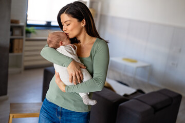 Loving mother carying of her newborn baby at home. Family parenting baby single mother love concept.