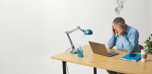 Exhausted man sitting at his desk with head in hands