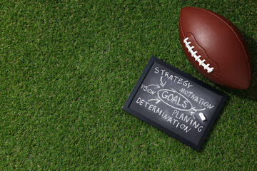 Black board with goal plan on grass with rugby ball