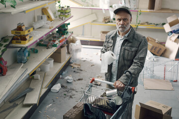Sad man doing grocery shopping in a destroyed supermarket