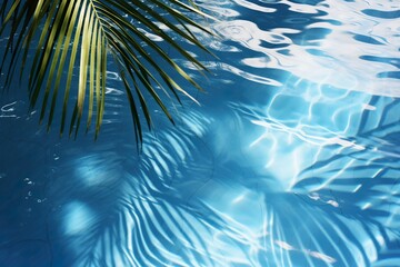 Fototapeta na wymiar Vibrant palm leaf shadows play on the surface of a tranquil, sunlit swimming pool with blue water. Vacation, holiday background. Empty, copy space for text.