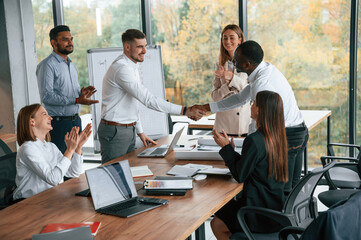 Successful agreement, making handshake. Group of office workers are together indoors