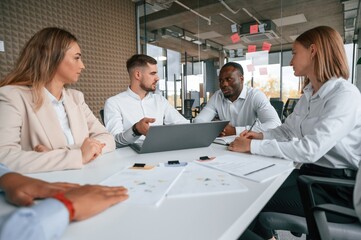Fototapeta premium Sitting together by the table. Group of office workers are indoors