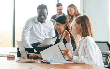 Wireless device on the table, laptop. Group of office workers are together indoors