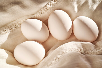 White chicken eggs on a white linen towel close-up.