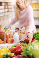 Obraz na płótnie Canvas Happy woman buying fresh healthy vegetables at the supermarket