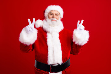 Photo of retired positive man santa claus demonstrate two arms v-sign good mood magic new year time isolated on red color background