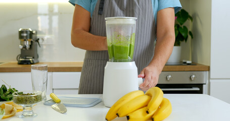 Man mixing bananas and spinach for delicious smoothie into blender