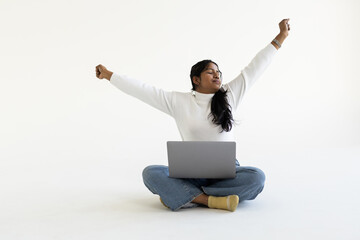 Indian woman using laptop and giving winning expression on white background.